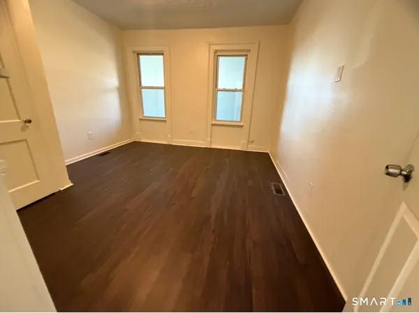a view of an empty room with wooden floor and a window