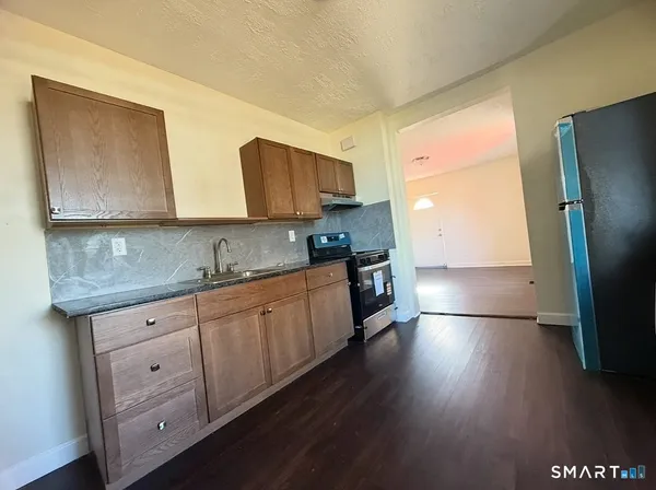 a kitchen with granite countertop a stove a sink and a refrigerator