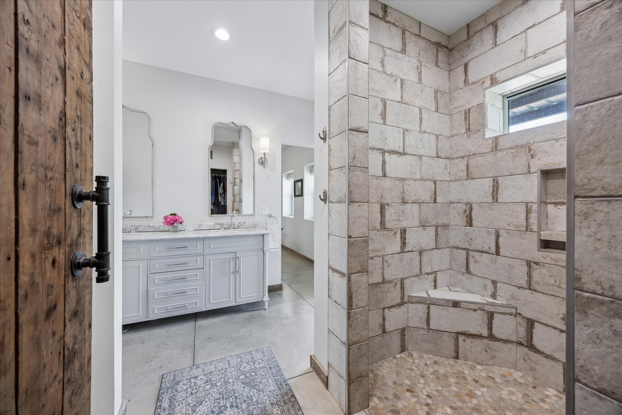 6411 West Fitzhugh Road Dripping Springs, TX 78620 - Photo 15 of 34 Walk-in shower featuring natural-tone stone tile walls with a built-in bench and a pebble floor
