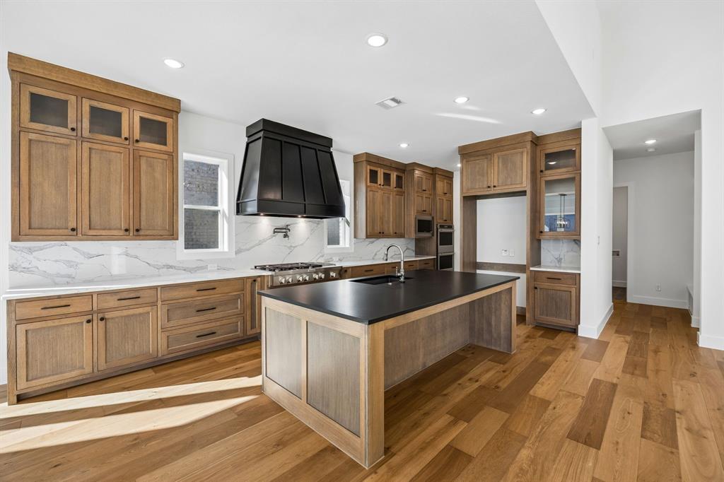 2404 Cairn Road McKinney, TX 75071 - Photo 5 of 18 This dream kitchen features beautiful wood tone cabinets, striking dark island counter top with matching dark vent hood and wonderful flooring that effortlessly blend to create a kitchen for the ages!