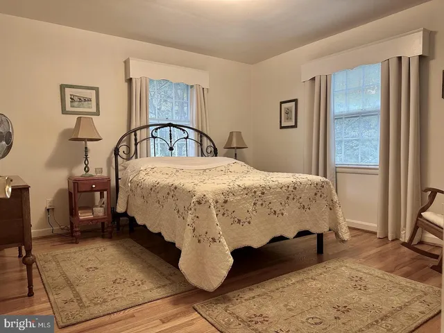 a bed sitting in a bedroom next to a window with chair
