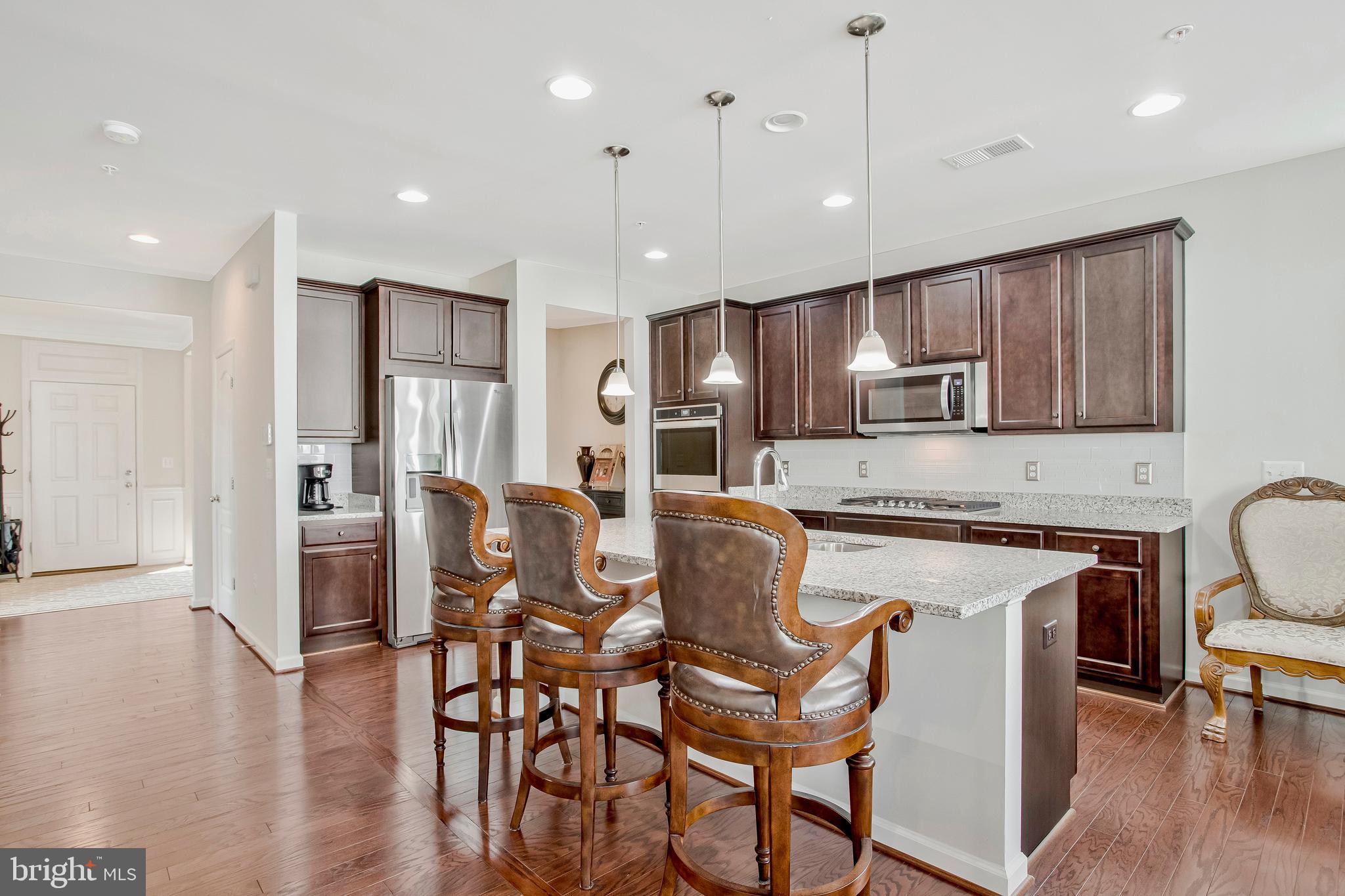 2123 Nottoway Drive Hanover, MD 21076 - Photo 10 of 57 a kitchen with stainless steel appliances granite countertop a stove top oven a refrigerator a sink and a dining table with wooden floor
