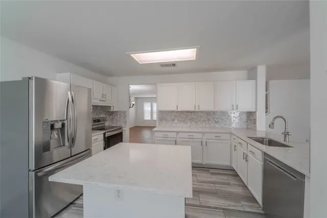 a kitchen with stainless steel appliances a refrigerator sink and microwave