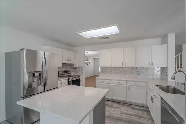 a kitchen with kitchen island a sink stove and refrigerator