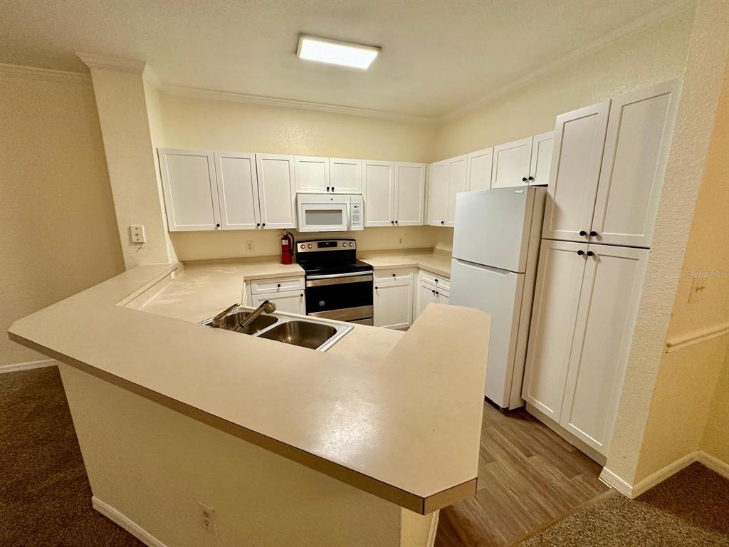 3561 Conroy Road, Unit 215 Orlando, FL 32839 - Photo 12 of 43 a kitchen with stainless steel appliances a refrigerator a stove a sink and white cabinets
