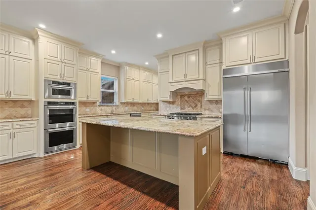 a kitchen with kitchen island granite countertop a sink cabinets and stainless steel appliances