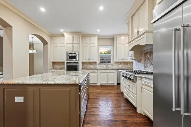 a kitchen with stainless steel appliances granite countertop a stove a sink and a refrigerator