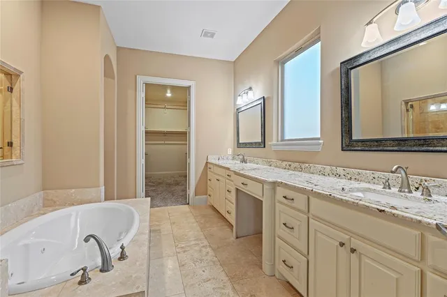 a spacious bathroom with a double vanity sink mirror and bathtub