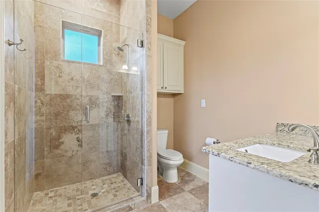 a bathroom with a granite countertop sink a toilet and shower