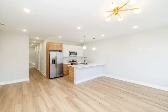 a kitchen with stainless steel appliances kitchen island wooden floors and white walls