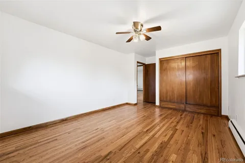 an empty room with wooden floor fan and windows