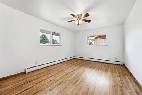 a view of empty room with wooden floor and fan