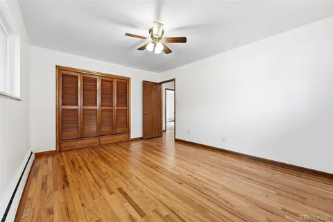 a view of empty room with wooden floor and fan