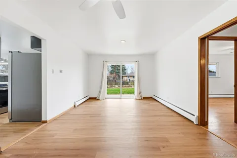 a view of an empty room with wooden floor and a window