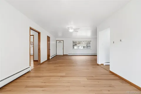 a view of an empty room with window and wooden floor