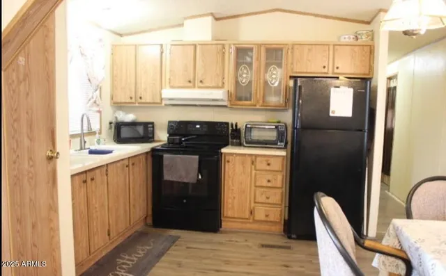 a kitchen with stainless steel appliances granite countertop a refrigerator a stove a sink dishwasher and wooden cabinets with wooden floor