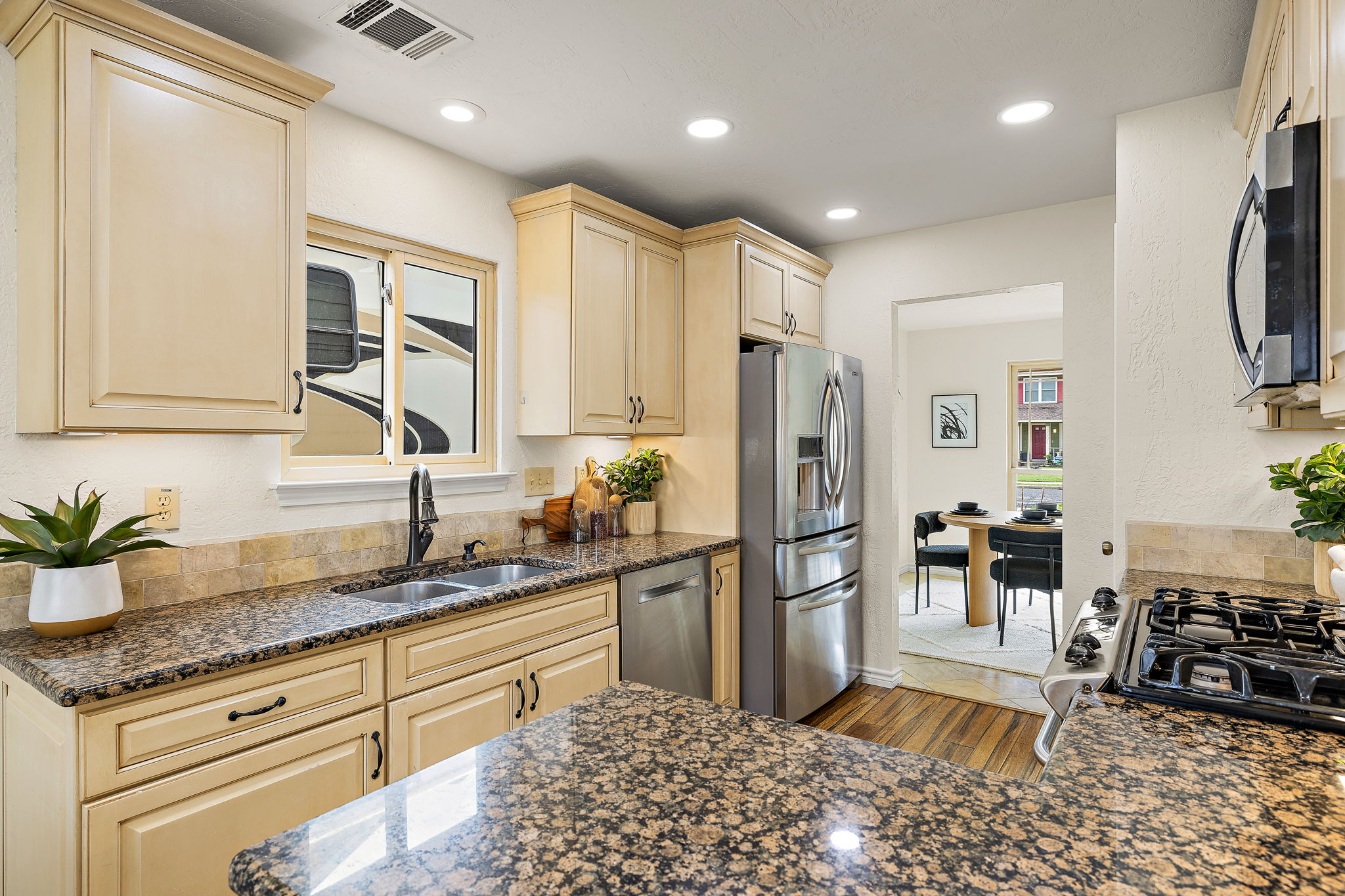 9002 Bancroft Trail Austin, TX 78729 - Photo 3 of 35 Kitchen with breakfast area and also opens to the formal dining room, window over the sink, granite countertops, pantry, recessed dimmable lighting, under-cabinet lighting