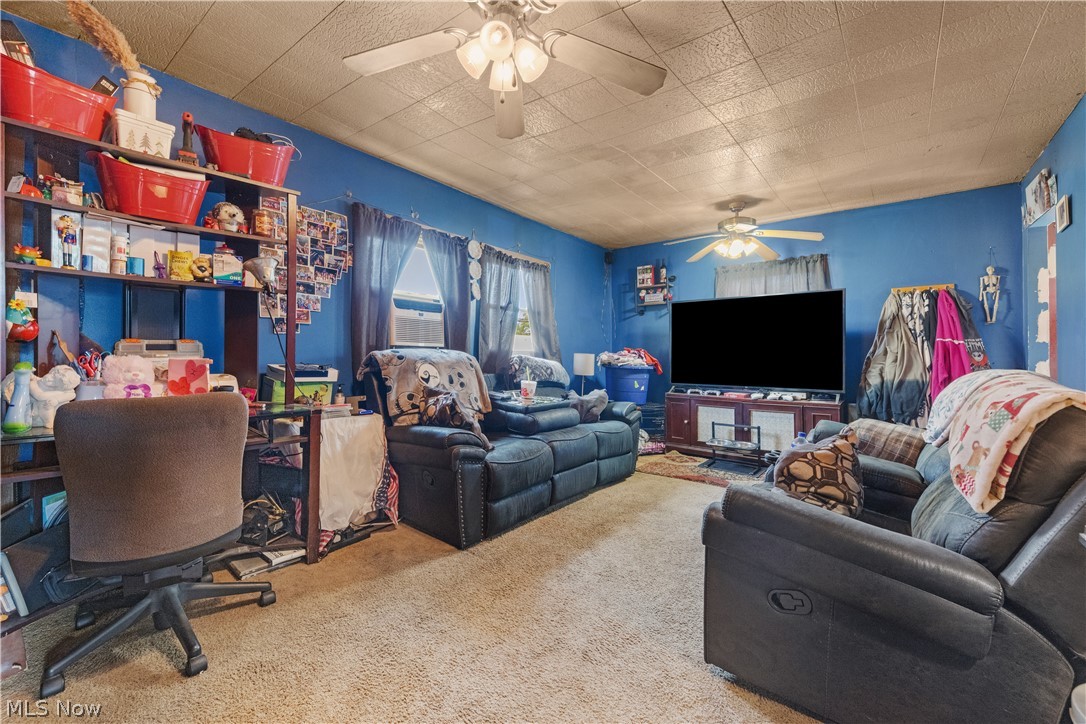 68-70 East Sunset Drive Rittman, OH 44270 - Photo 6 of 49 Living area featuring carpeting, blue walls, a textured ceiling, and two ceiling fans with light kits