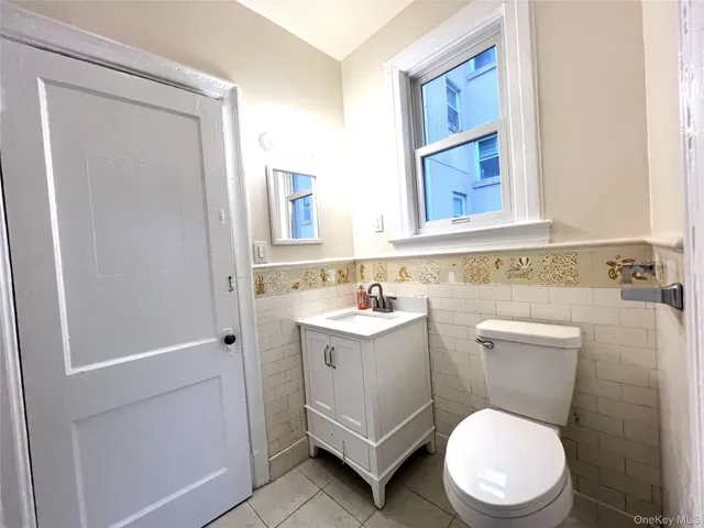 a bathroom with a toilet a sink a mirror a vanity and a window