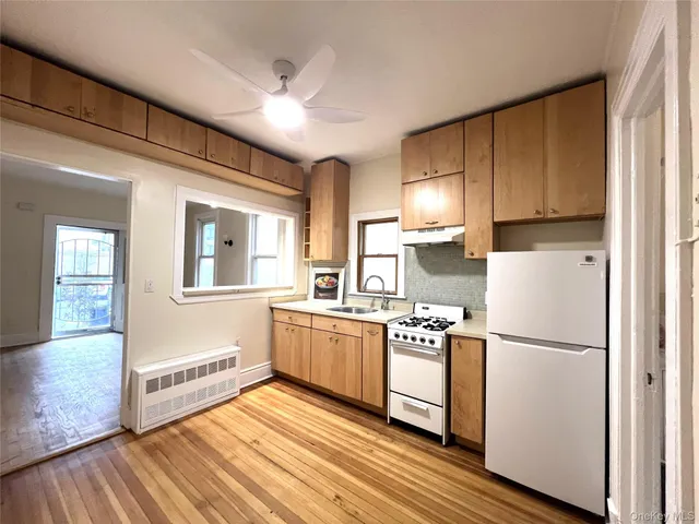 a kitchen with stainless steel appliances granite countertop a refrigerator a sink dishwasher a stove and white countertops with wooden floor