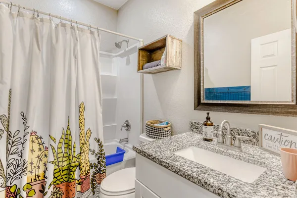 a bathroom with a granite countertop sink and a mirror with toilet