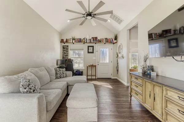 a living room with furniture and a kitchen with wooden floor