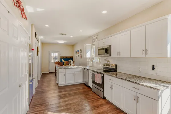 a kitchen with granite countertop white cabinets and stainless steel appliances