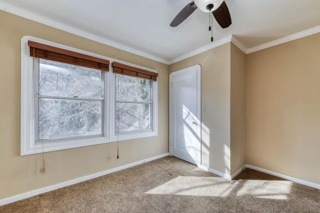 a view of an empty room with window and a kitchen view