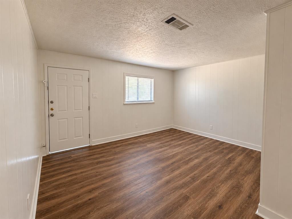 2002 Washington Street, Unit 3 Commerce, TX 75428 - Photo 4 of 8 Wood-finish flooring with white baseboards, vertical paneling, and a panel door with multiple lites