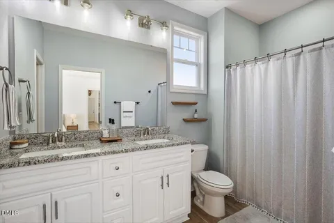 a bathroom with a granite countertop sink toilet and mirror