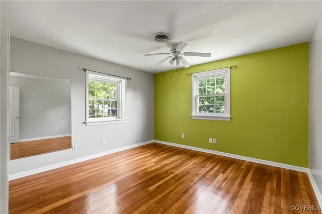 a view of empty room with wooden floor and fan