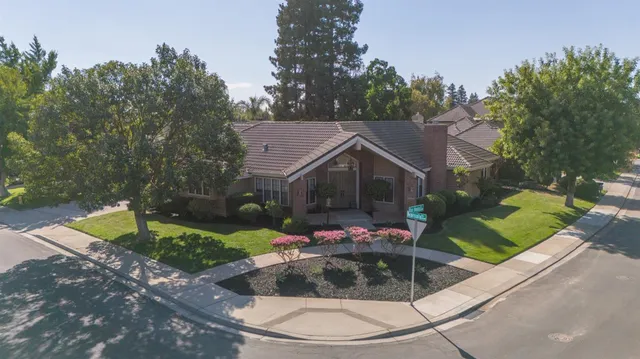 a view of a house with a yard and large tree
