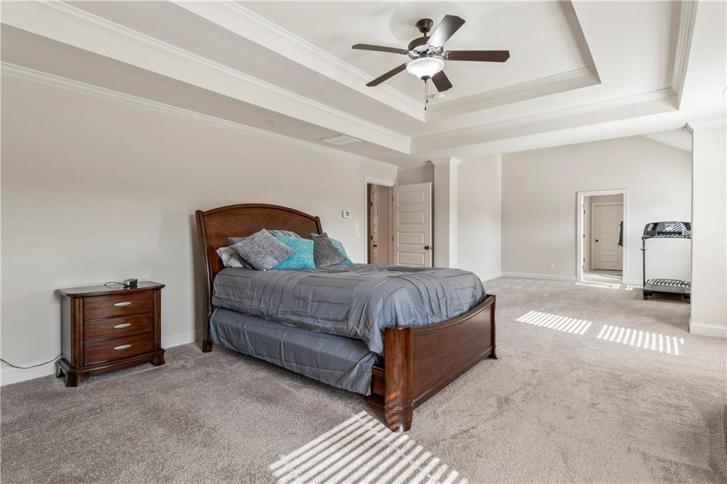 7004 Becca Lane Locust Grove, GA 30248 - Photo 26 of 39 a spacious bedroom with a bed a dresser and a chandelier