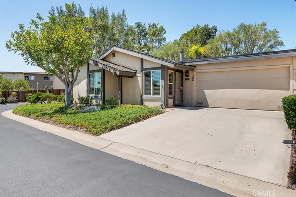 a white house with a large tree plants