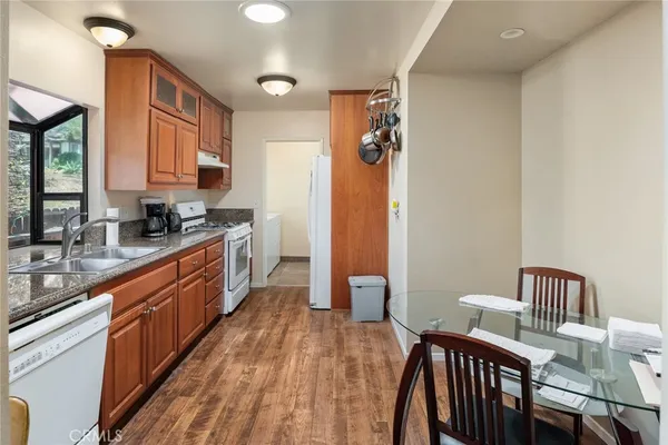 a kitchen with stainless steel appliances granite countertop a sink a stove and a wooden floors