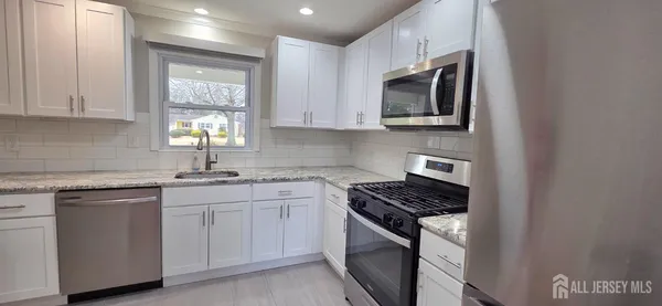 a kitchen with cabinets appliances a sink and a window