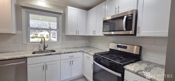 a kitchen with stainless steel appliances granite countertop white cabinets and window