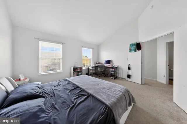a bed sitting in a bedroom next to a window with tv and a couch