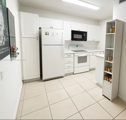 a white refrigerator freezer and a stove sitting inside of a kitchen with stainless steel appliances