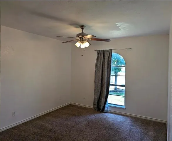 an empty room with windows and chandelier fan