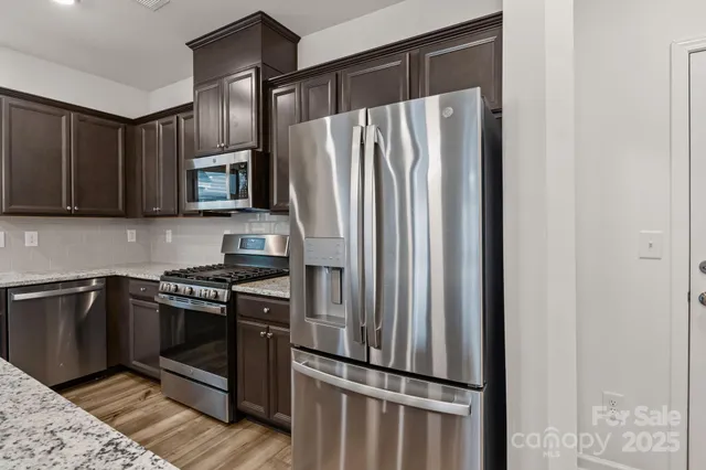 a kitchen with granite countertop a refrigerator stove and microwave