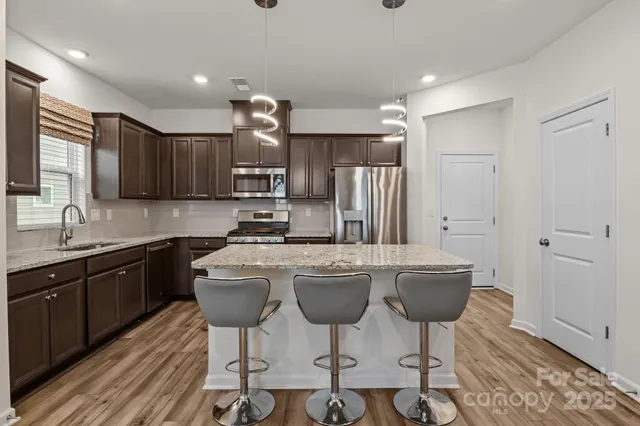 a kitchen with refrigerator a sink and chairs