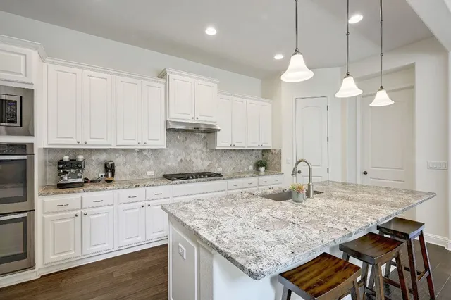 a kitchen with kitchen island granite countertop a sink a center island a counter space and cabinets