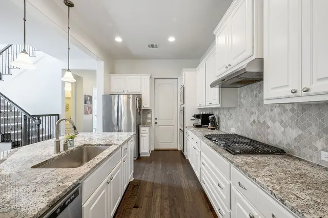a kitchen with stainless steel appliances granite countertop a sink stove and refrigerator