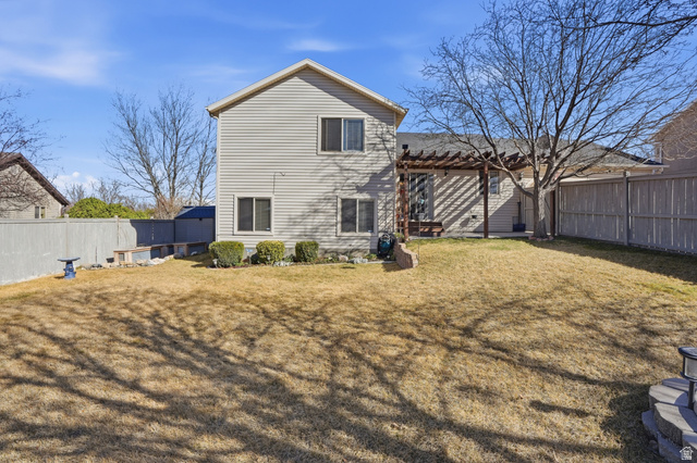 7737 Ranches Parkway Eagle Mountain, UT 84005 - Photo 24 of 28 Expansive backyard featuring a large lawn area, a wooden pergola, and established perimeter fencing
