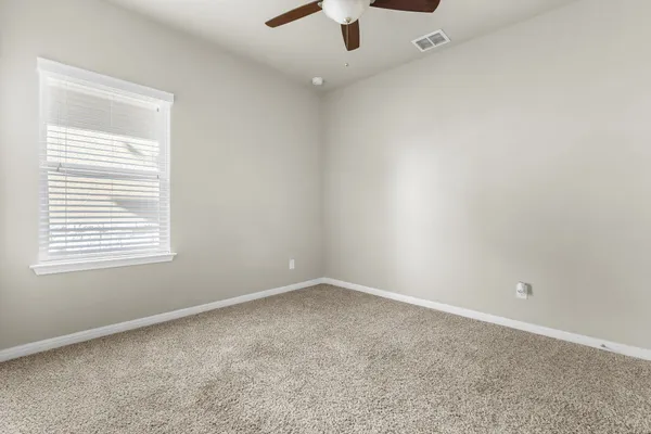 an empty room with a window and a fan