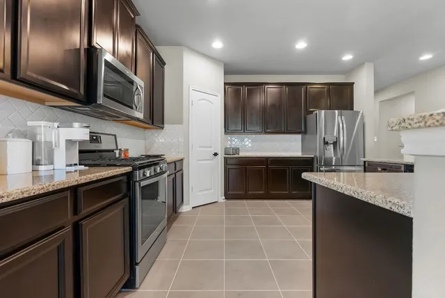 a large kitchen with stainless steel appliances granite countertop a stove top oven a sink and dishwasher
