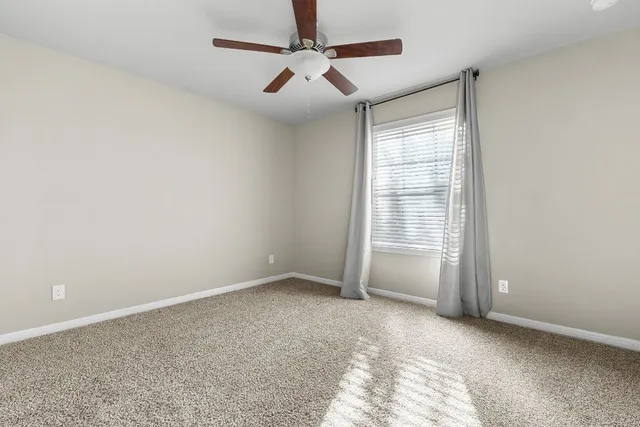 a view of an empty room and chandelier fan