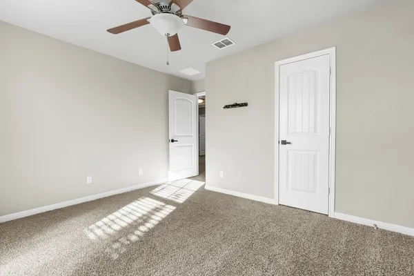 a view of an empty room and chandelier fan