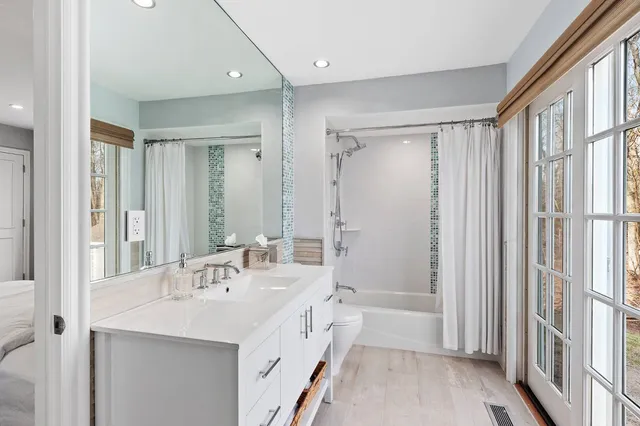 a bathroom with a double vanity sink a mirror a bathtub and shower